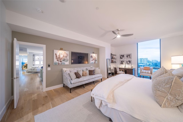 bedroom featuring light wood-type flooring, multiple windows, baseboards, and ceiling fan