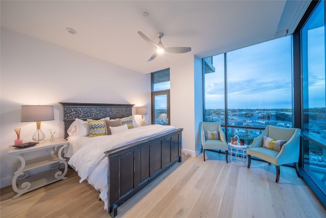 bedroom featuring expansive windows, light wood-style floors, and ceiling fan