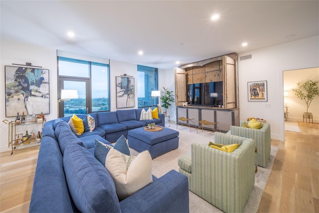 living area with recessed lighting, visible vents, light wood finished floors, and baseboards