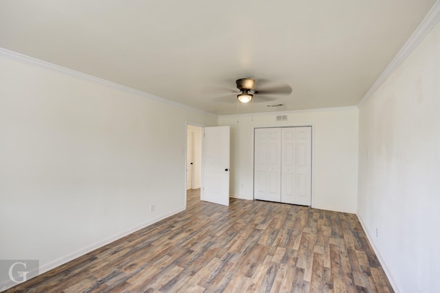 unfurnished bedroom with hardwood / wood-style flooring, ornamental molding, ceiling fan, and a closet