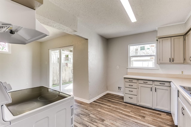 kitchen featuring white electric stove, light countertops, light wood-style floors, a textured ceiling, and extractor fan