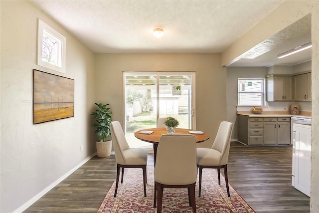 unfurnished dining area featuring a textured ceiling, baseboards, dark wood-style flooring, and a textured wall