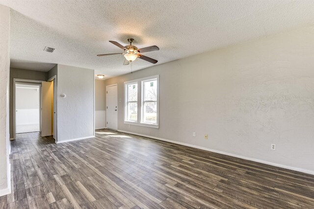 doorway with a textured ceiling, a textured wall, dark wood-style flooring, and baseboards