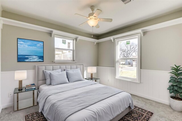 spare room featuring light colored carpet, wainscoting, and a healthy amount of sunlight