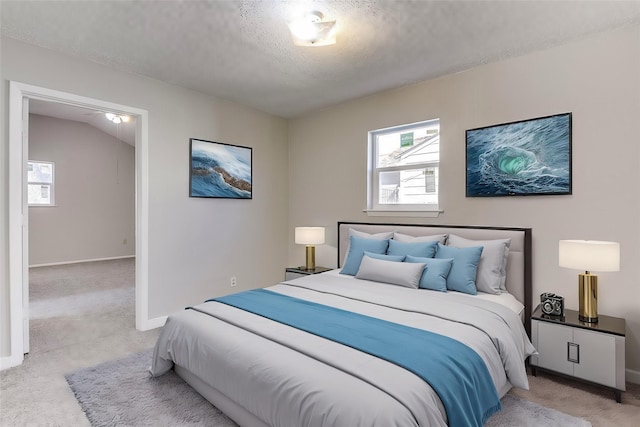 bedroom featuring light carpet, a textured ceiling, and baseboards