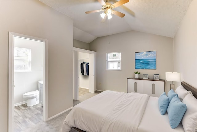 bedroom with vaulted ceiling, ensuite bath, a ceiling fan, and baseboards