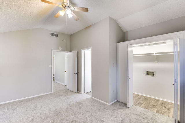 unfurnished bedroom featuring vaulted ceiling, a textured ceiling, visible vents, and light colored carpet