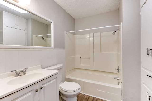 bathroom with a textured ceiling, toilet, wood finished floors, bathing tub / shower combination, and vanity