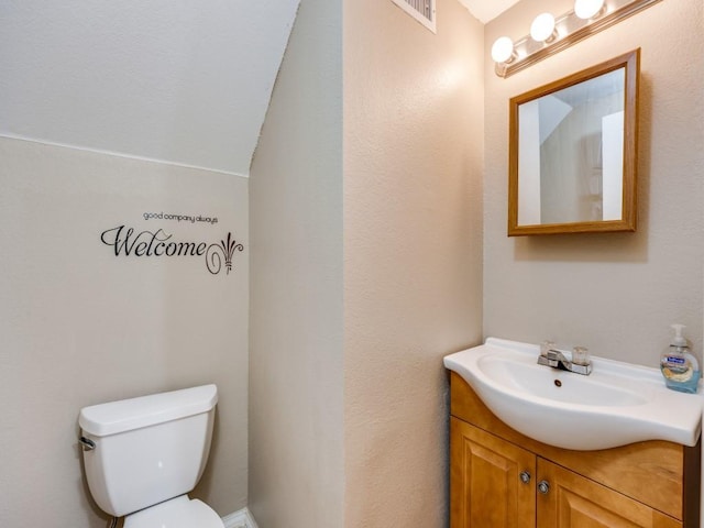 bathroom with vanity, lofted ceiling, and toilet