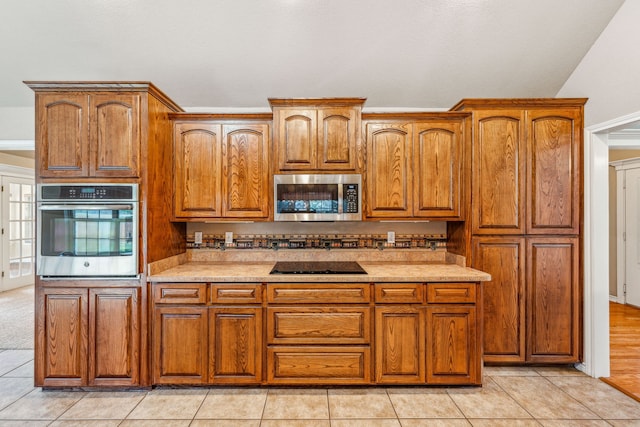 kitchen featuring light tile patterned flooring, appliances with stainless steel finishes, and lofted ceiling