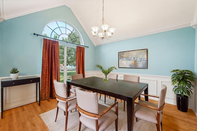 dining room with ornamental molding, lofted ceiling, a notable chandelier, and light wood-type flooring