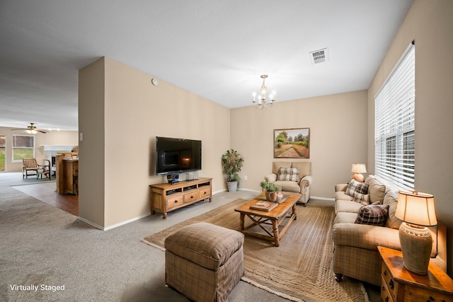 carpeted living room featuring ceiling fan with notable chandelier