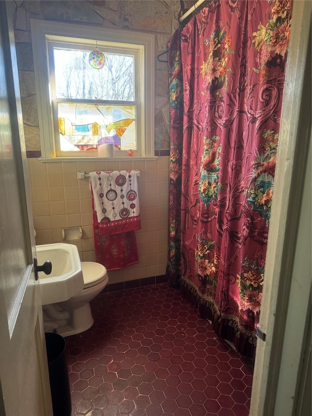 bathroom featuring tile patterned flooring, sink, tile walls, and toilet