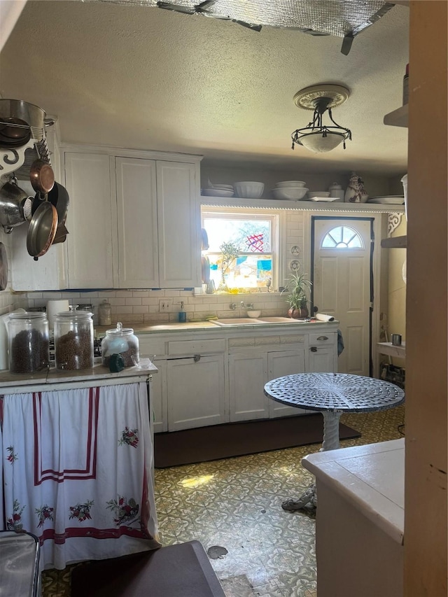 kitchen featuring white cabinetry, sink, backsplash, and a textured ceiling