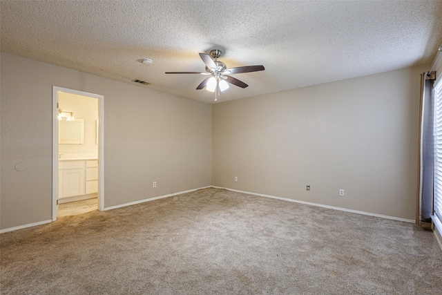 unfurnished bedroom with ceiling fan, light colored carpet, a textured ceiling, and ensuite bath