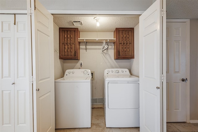 laundry room with cabinets, separate washer and dryer, and a textured ceiling