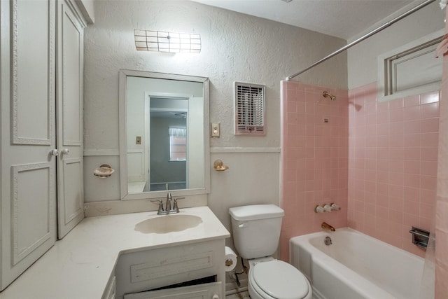 full bathroom featuring vanity, tiled shower / bath combo, and toilet