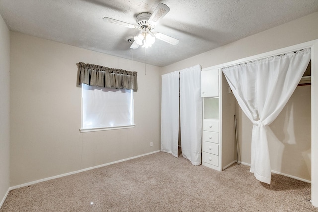 unfurnished bedroom featuring ceiling fan, light carpet, and a textured ceiling