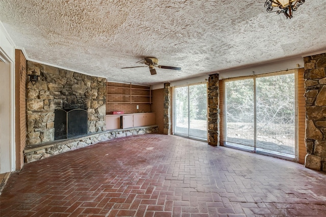 unfurnished living room with a stone fireplace, a textured ceiling, and ceiling fan