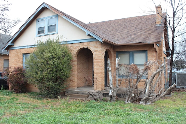 tudor house with a front yard and cooling unit