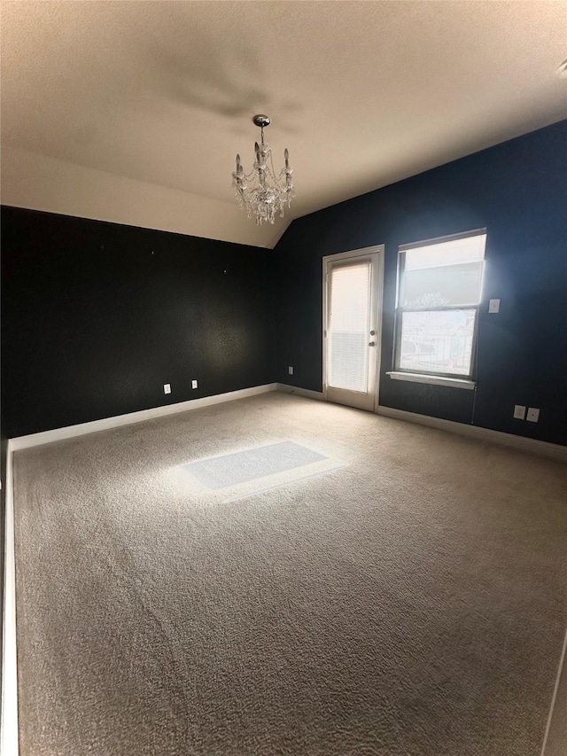 carpeted spare room with lofted ceiling, a textured ceiling, and a notable chandelier