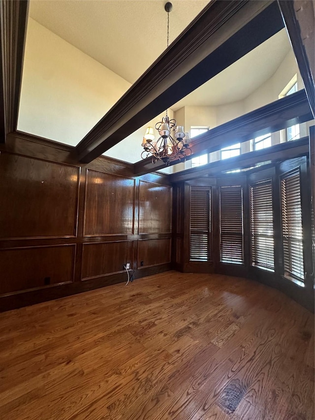 interior space featuring ornamental molding, dark wood-type flooring, wooden walls, and an inviting chandelier