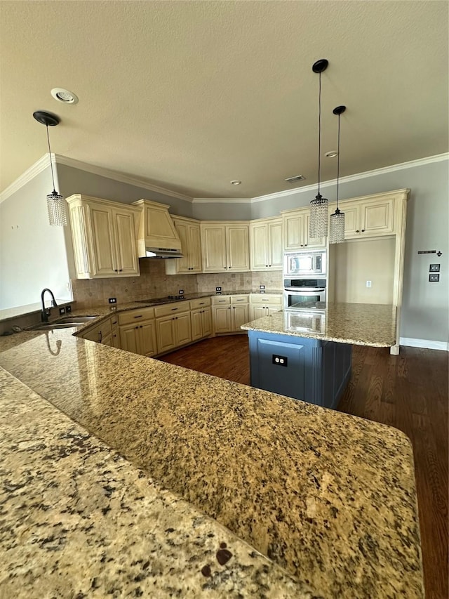 kitchen with custom exhaust hood, a sink, ornamental molding, stainless steel appliances, and cream cabinetry