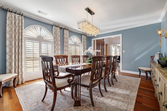 dining area with ornamental molding, dark wood-type flooring, and an inviting chandelier