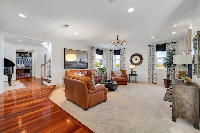 living room featuring an inviting chandelier, ornamental molding, a healthy amount of sunlight, and light hardwood / wood-style floors