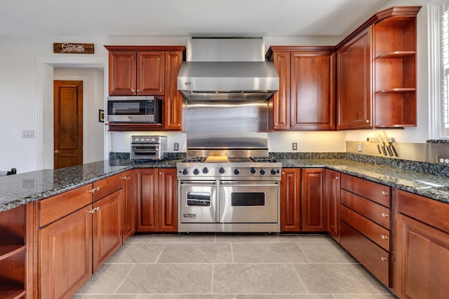 kitchen featuring dark stone countertops, stainless steel appliances, and wall chimney range hood