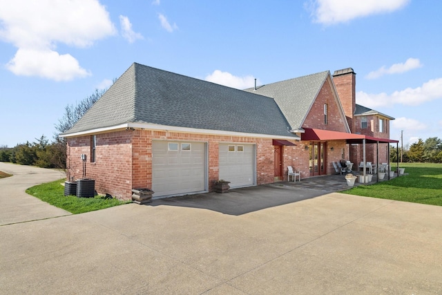 view of side of property featuring a garage, a yard, and central AC unit