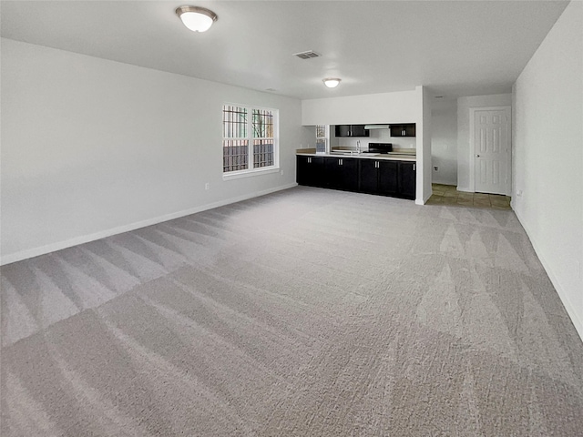 unfurnished living room with sink and light colored carpet