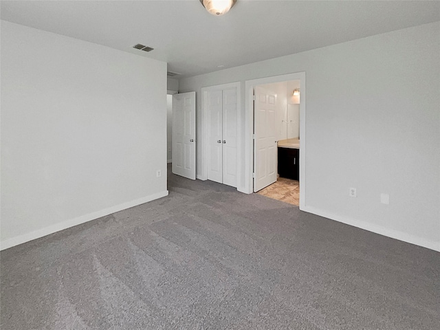 unfurnished bedroom featuring light colored carpet and ensuite bathroom