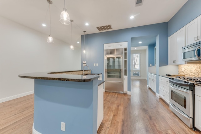 kitchen featuring tasteful backsplash, decorative light fixtures, stainless steel appliances, light hardwood / wood-style floors, and white cabinets