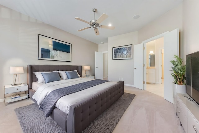 bedroom with ceiling fan, light colored carpet, and connected bathroom