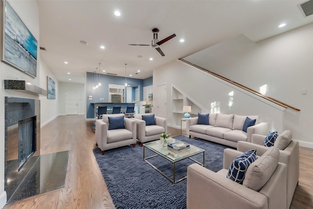 living room with hardwood / wood-style flooring, ceiling fan, and a fireplace