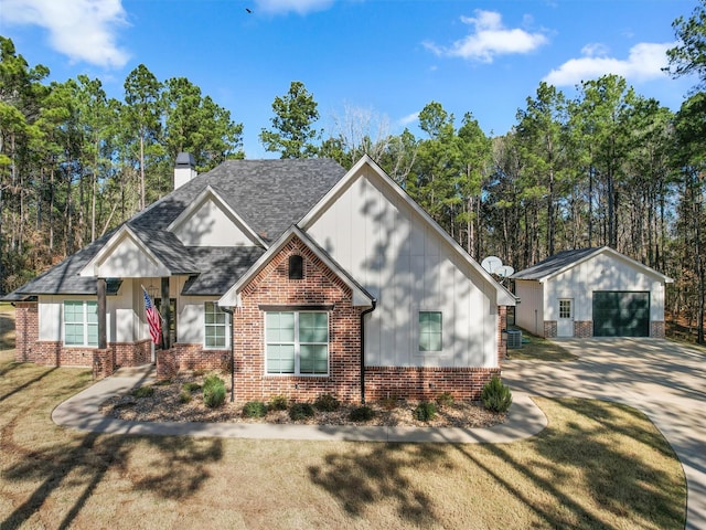 view of front of home featuring a garage, an outdoor structure, and a front lawn