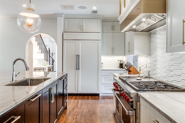 kitchen with dark hardwood / wood-style floors, sink, custom exhaust hood, high end appliances, and light stone countertops