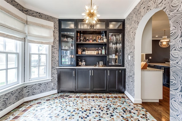 bar featuring crown molding, a notable chandelier, decorative light fixtures, and hardwood / wood-style flooring