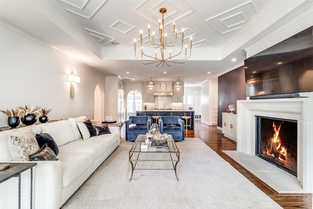 living room with crown molding, wood-type flooring, a raised ceiling, and sink