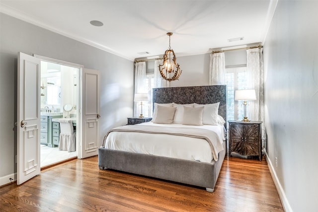 bedroom featuring hardwood / wood-style flooring, ensuite bathroom, and a notable chandelier