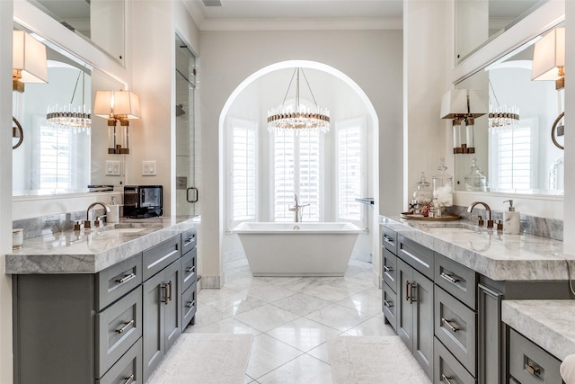 bathroom with ornamental molding, a bath, vanity, and a chandelier