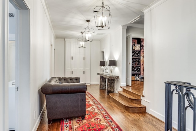 sitting room with wood-type flooring, ornamental molding, and a chandelier