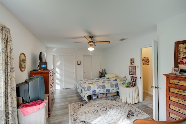 bedroom with multiple closets, ceiling fan, and light hardwood / wood-style floors