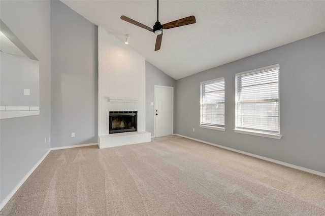 unfurnished living room with high vaulted ceiling, light colored carpet, ceiling fan, a brick fireplace, and a textured ceiling