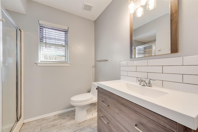 bathroom with vanity, decorative backsplash, a shower with door, and toilet