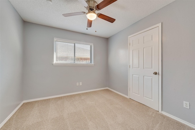 unfurnished room with ceiling fan, light carpet, and a textured ceiling