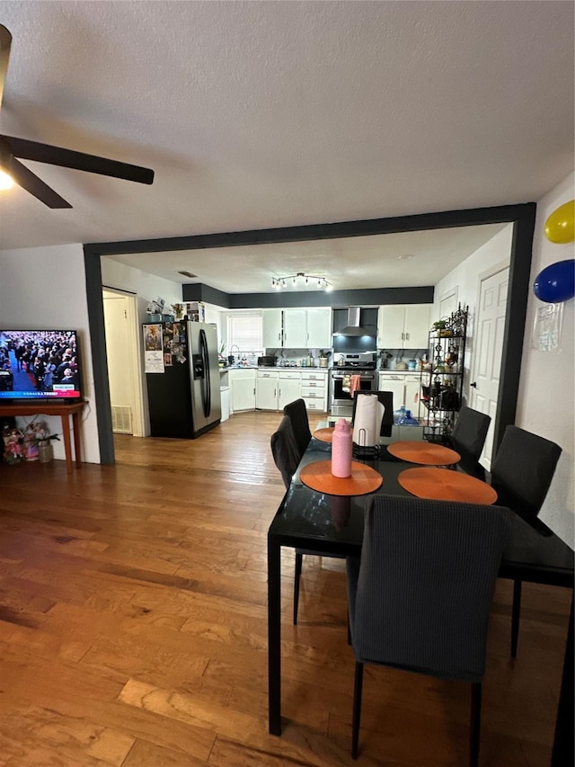 dining space with ceiling fan, a textured ceiling, and light hardwood / wood-style floors