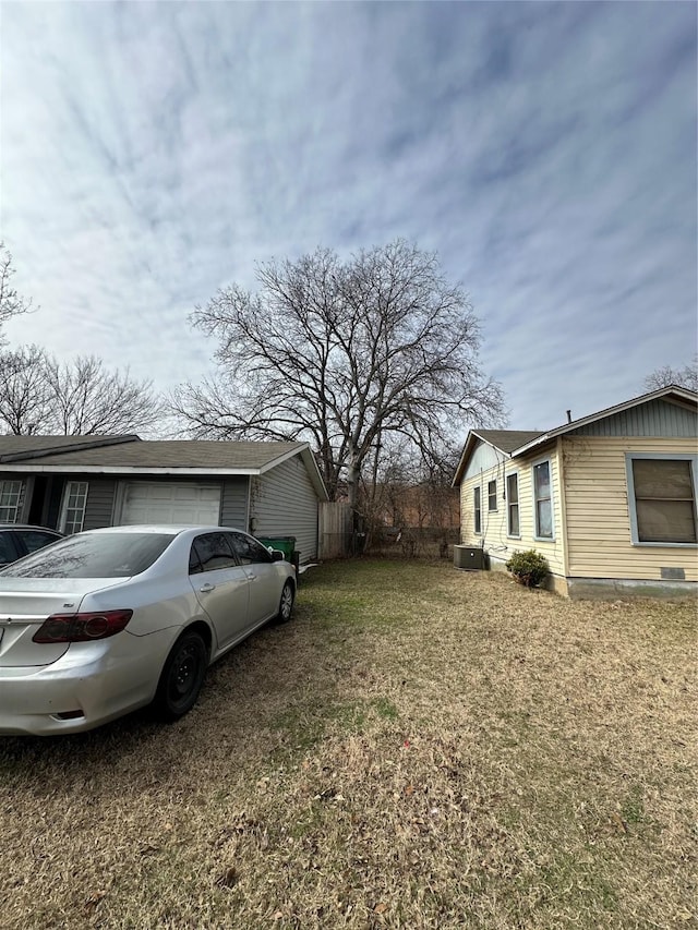 view of home's exterior with a garage, a lawn, and central AC