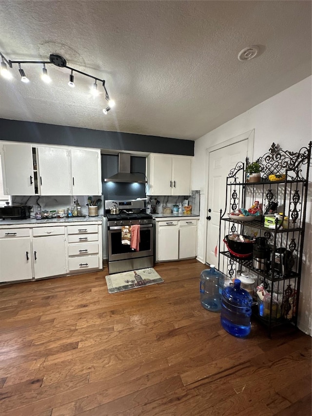 kitchen featuring white cabinetry, gas stove, hardwood / wood-style flooring, and wall chimney exhaust hood